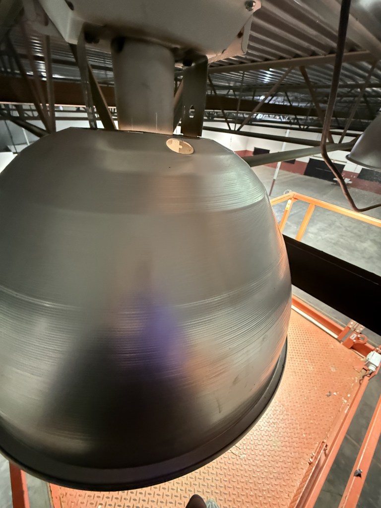Industrial light fixture being cleaned during commercial high dusting
