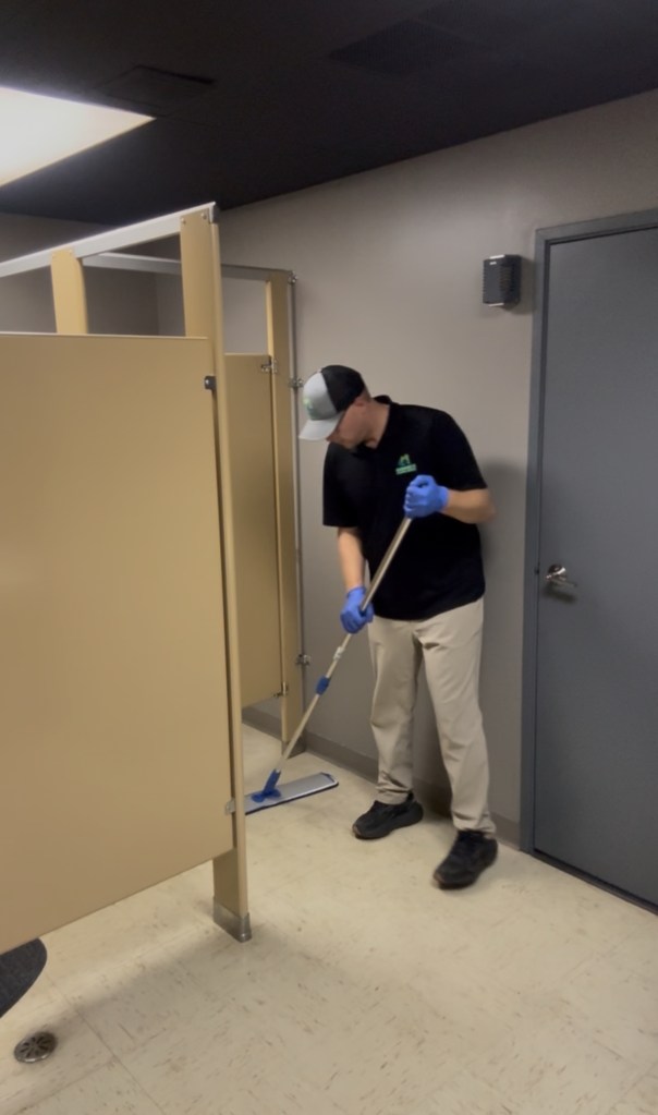 Cleaner mopping the floor in a commercial restroom